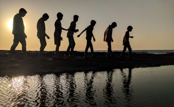 group of children walking near body of water silhouette photography