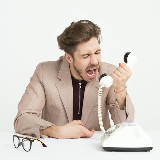 man wearing brown suit jacket mocking on white telephone